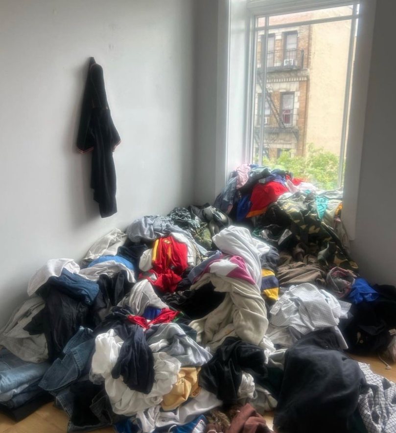 A large pile of discarded clothing on a bedroom floor